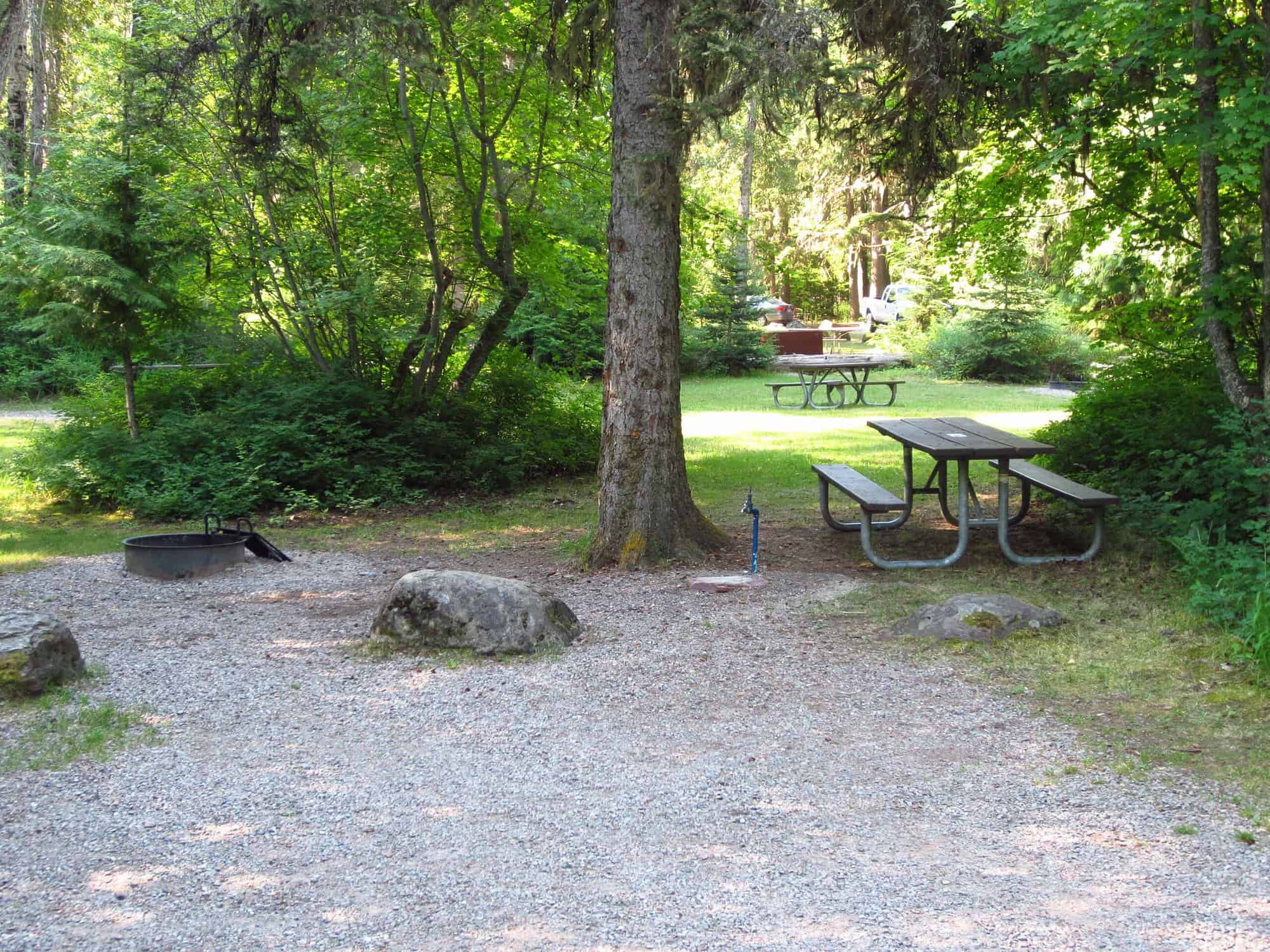 Sprague Creek Campground shoreline at Lake McDonald showing a shallow pebbly beach with clear water and forested hillsides in Glacier National Park