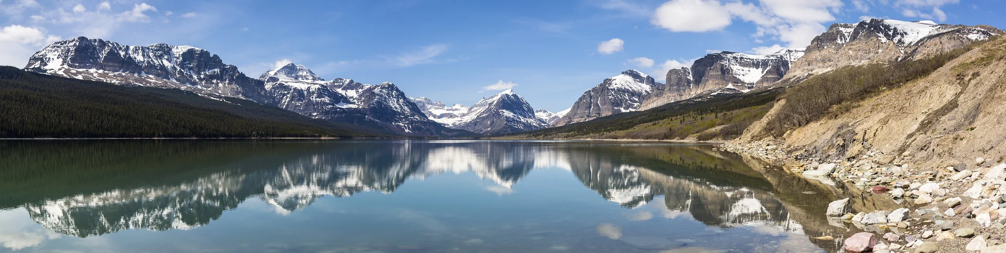 Lake Sherburne panorama in Many Glacier area of Glacier National Park, rugged mountains reflecting in still water