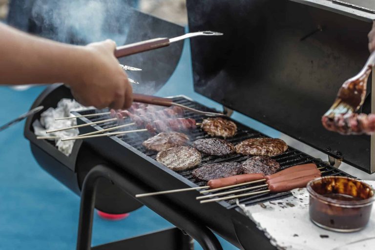 person grilling sausage and meat on one of the Best Camping Grills