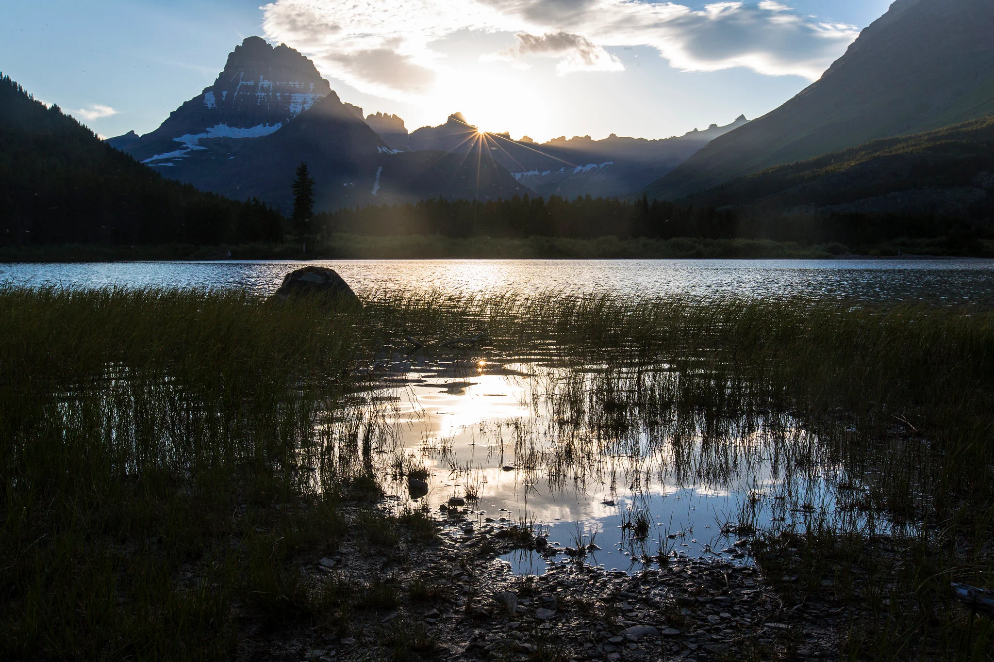 Sunset over Swiftcurrent Lake in the Many Glacier area of Glacier National Park, with mountain peaks reflected in calm water