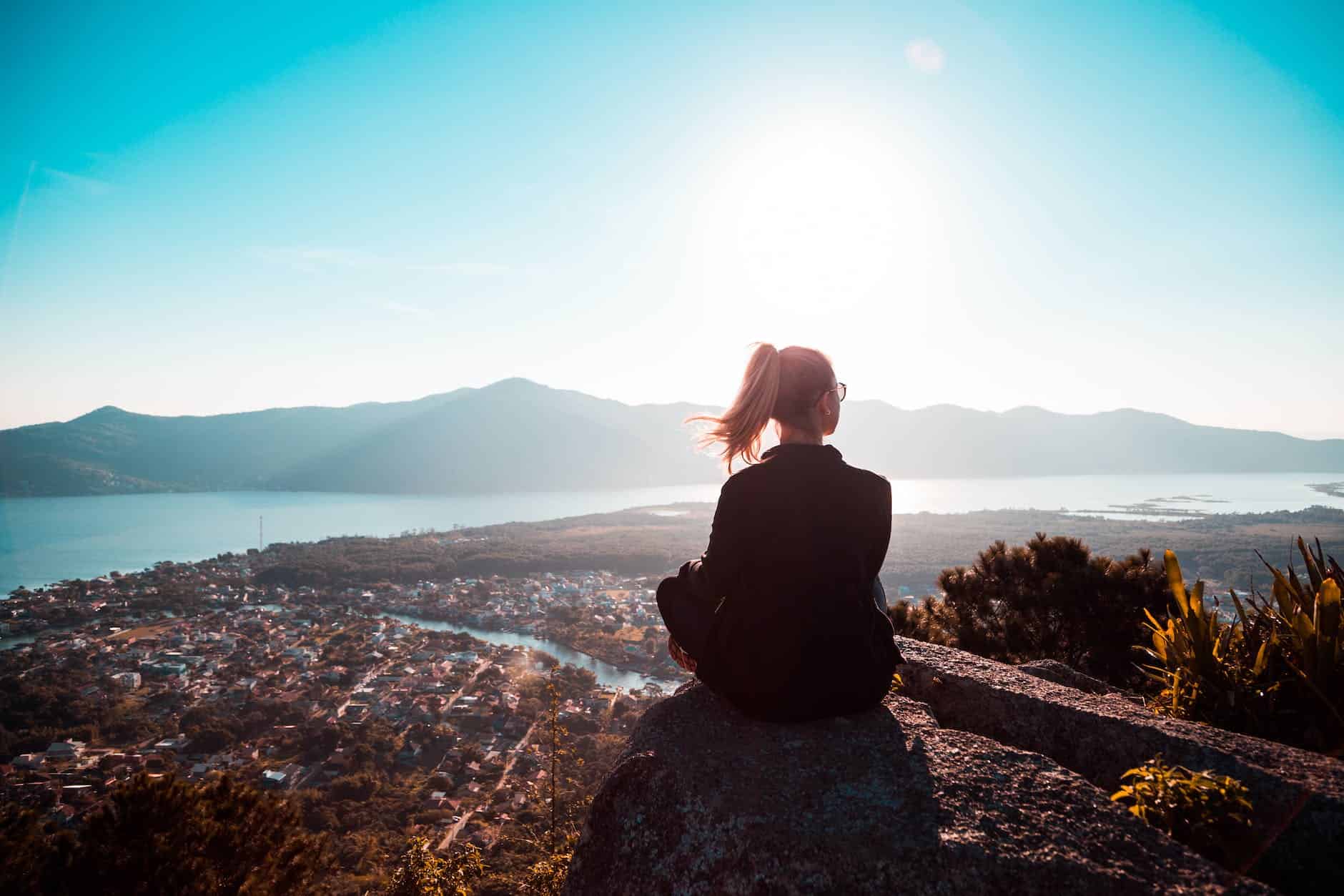 Visitor sitting at a mountain summit overlook with sweeping views of valleys and peaks near Glacier National Park