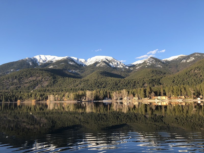 Lake Blaine in Glacier National Park reflects snow‑capped peaks and evergreen forests on a calm morning.