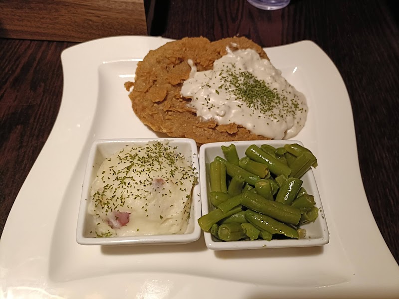 Crispy fried chicken with white sauce and herbs, dill potatoes, and green beans on a white plate in Yellowstone National Park.