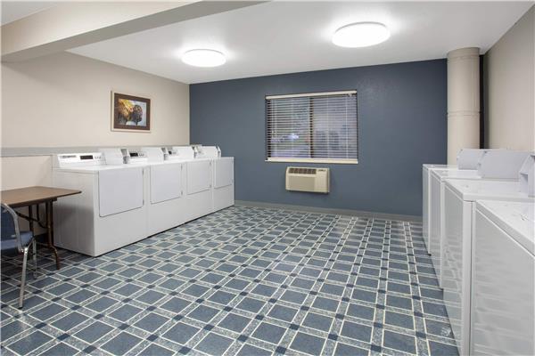 Laundromat-style lodge laundry in Yellowstone National Park with white machines along walls, blue floor, window, and heater.
