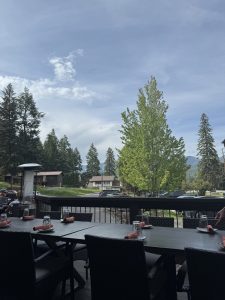 Outdoor restaurant patio in Glacier National Park with wicker tables, glassware, and a bright blue sky.