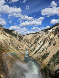 Trailhead with a rustic wooden sign and stone path at the exterior entrance