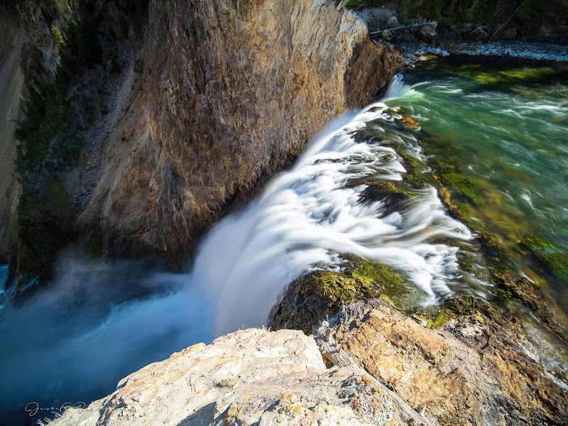 Brink of Lower Falls spills over rugged limestone cliffs into a turquoise pool at Yellowstone National Park.