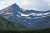 Snow-dusted jagged peaks rise above evergreen forests as Mount Siyeh towers over the glacier-carved valley in Glacier National Park.