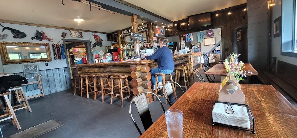 Inside Glacier National Park, a rustic log-bar with wooden stools at the counter, and several wooden tables.