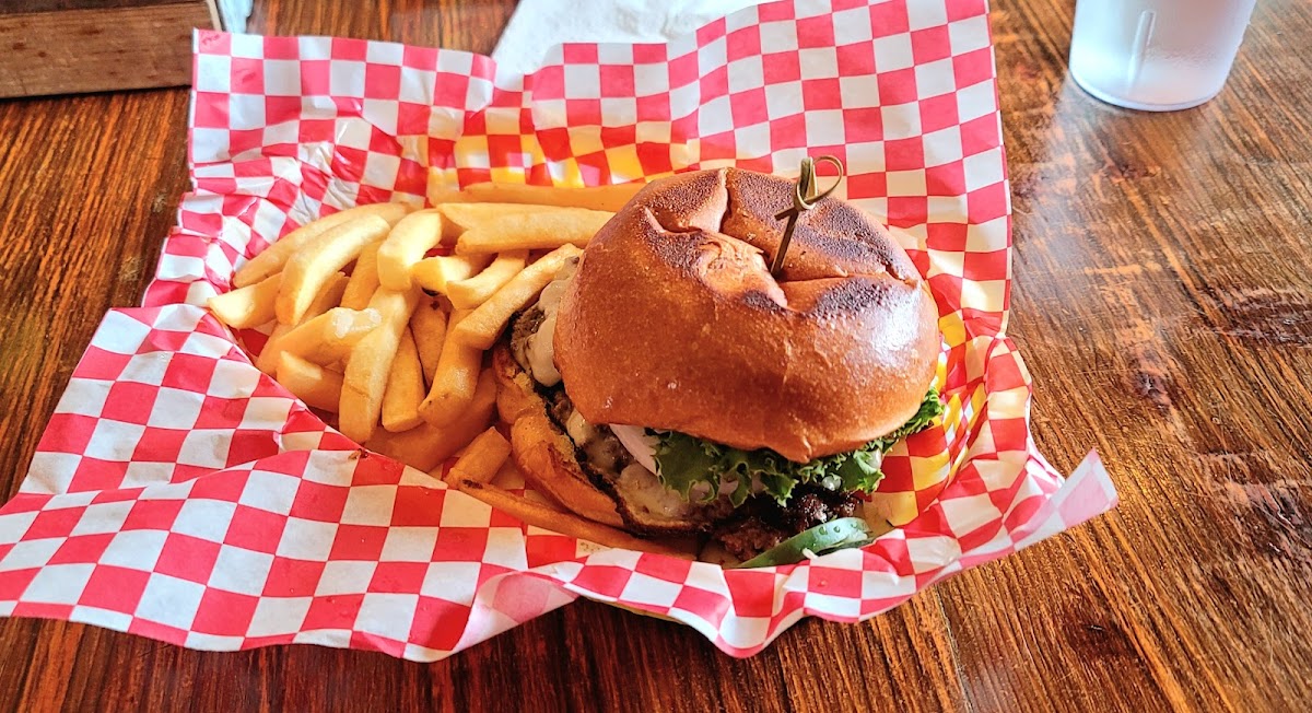 Burger with lettuce and cheese on a toasted bun beside a heap of fries on red and white checker paper in Glacier National Park.