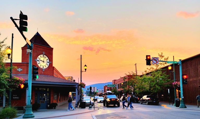 Downtown Whitefish town square with a brick clock tower at sunset near Glacier National Park.