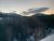 Lake Five overlook in Glacier National Park at sunset, with snow-covered pines and distant mountains.
