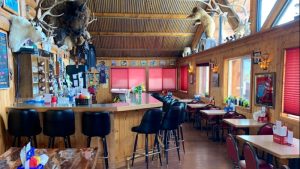 Exterior view of a rustic pub storefront with wooden beams and a hanging sign
