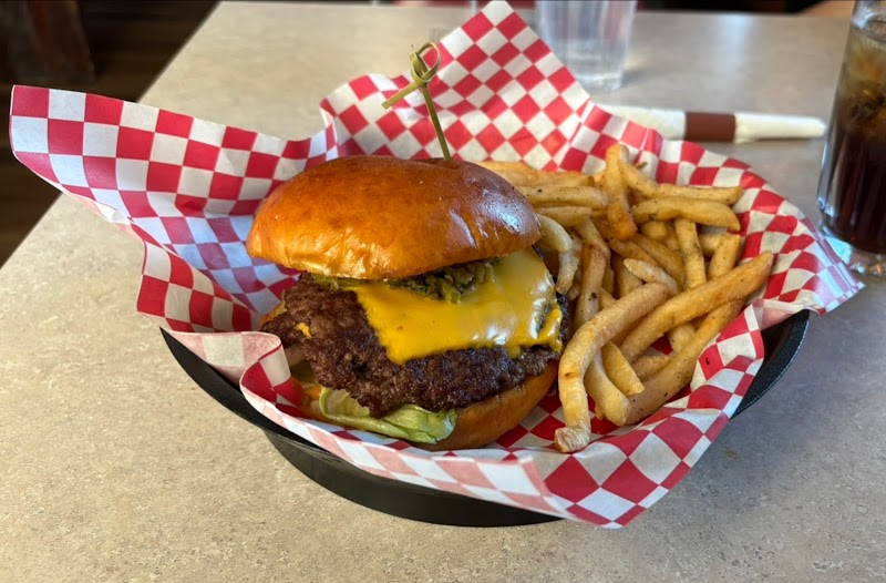 Juicy cheeseburger with cheddar and lettuce beside golden fries on red checker paper at Yellowstone National Park.