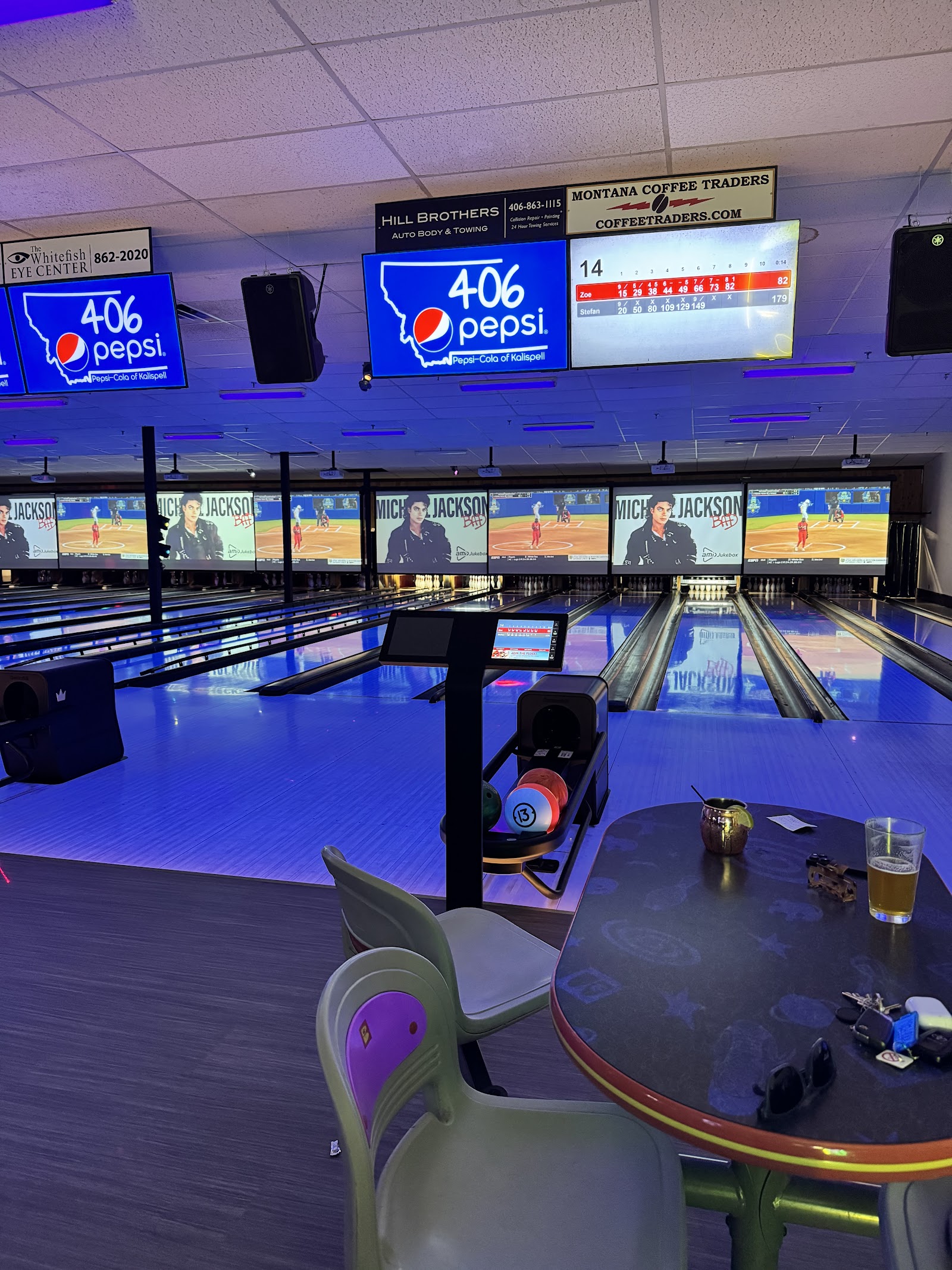 Indoor bowling alley at Pin & Cue in Glacier National Park, with neon-lit screens, polished lanes, and seating area.