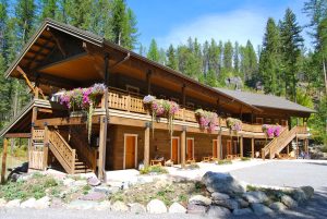 Wooden lodge with hanging flower baskets along a two-story balcony in Glacier National Park.