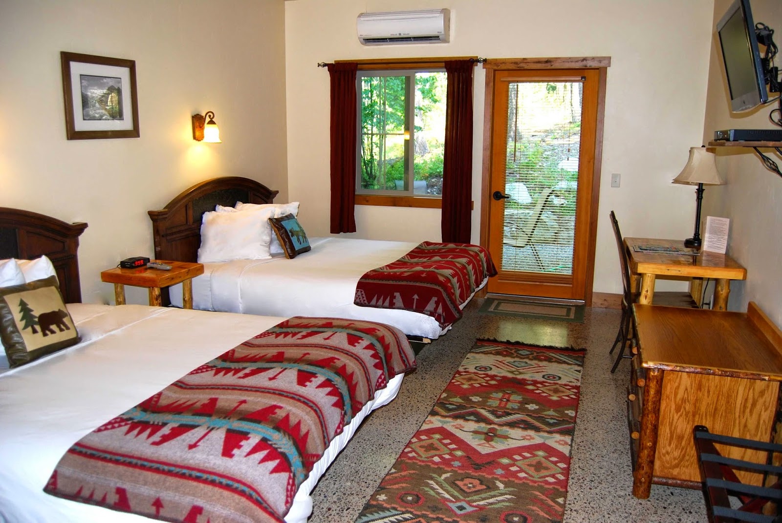 Guest room at Glacier National Park with two beds, rustic wood headboards, and warm lighting in a cozy lodge-style setting.