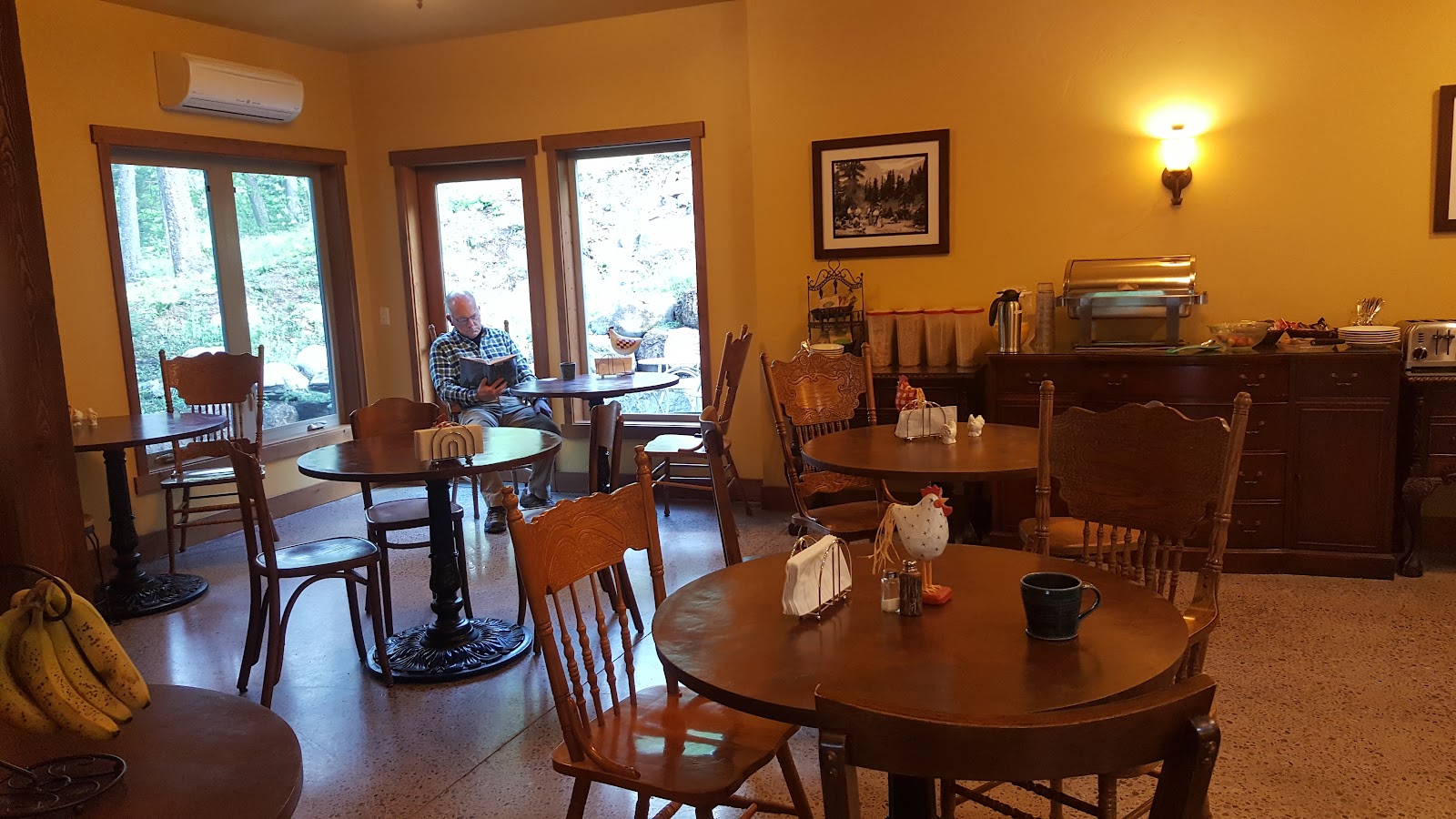 Cozy lodge common room with wooden tables and chairs inside a Glacier National Park lodge.