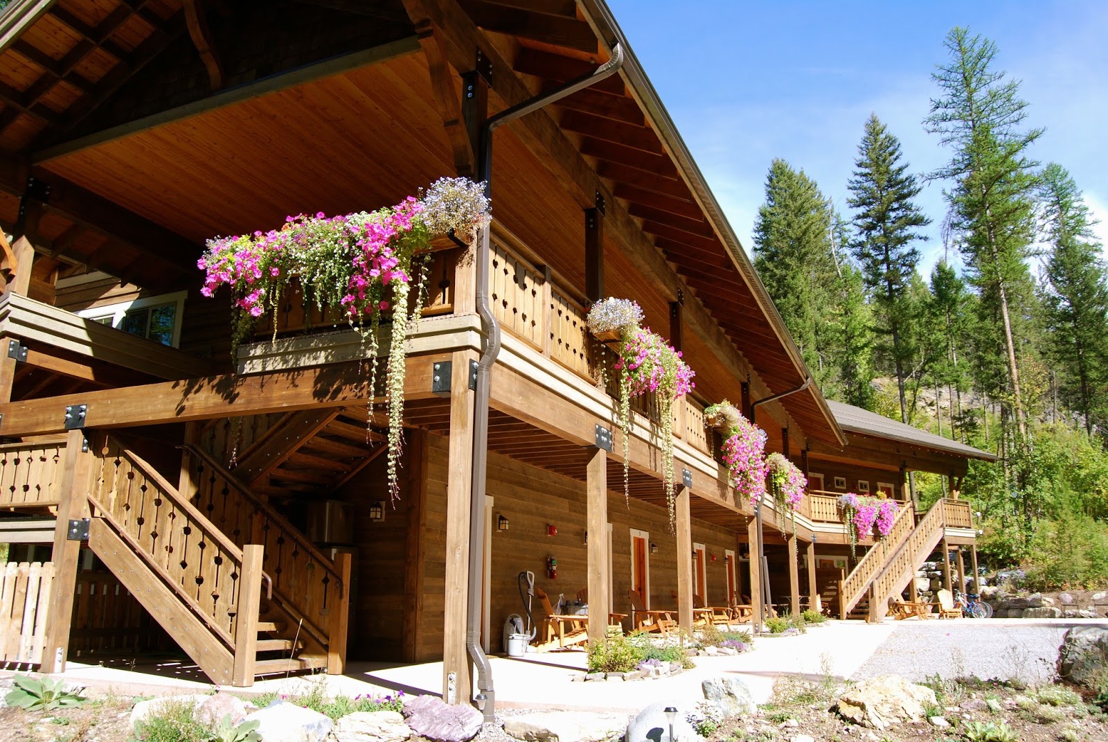 Exterior shot of Glacier Guides Lodge in Glacier National Park, with wooden balconies and hanging flower baskets along the veranda.