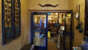 Glacier National Park restaurant entrance with glass doors, warm lighting, and decorative wrought-iron elements.