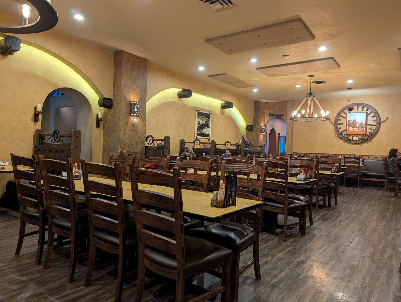 Warm, wood-paneled dining room with long tables and chandeliers in Glacier National Park.