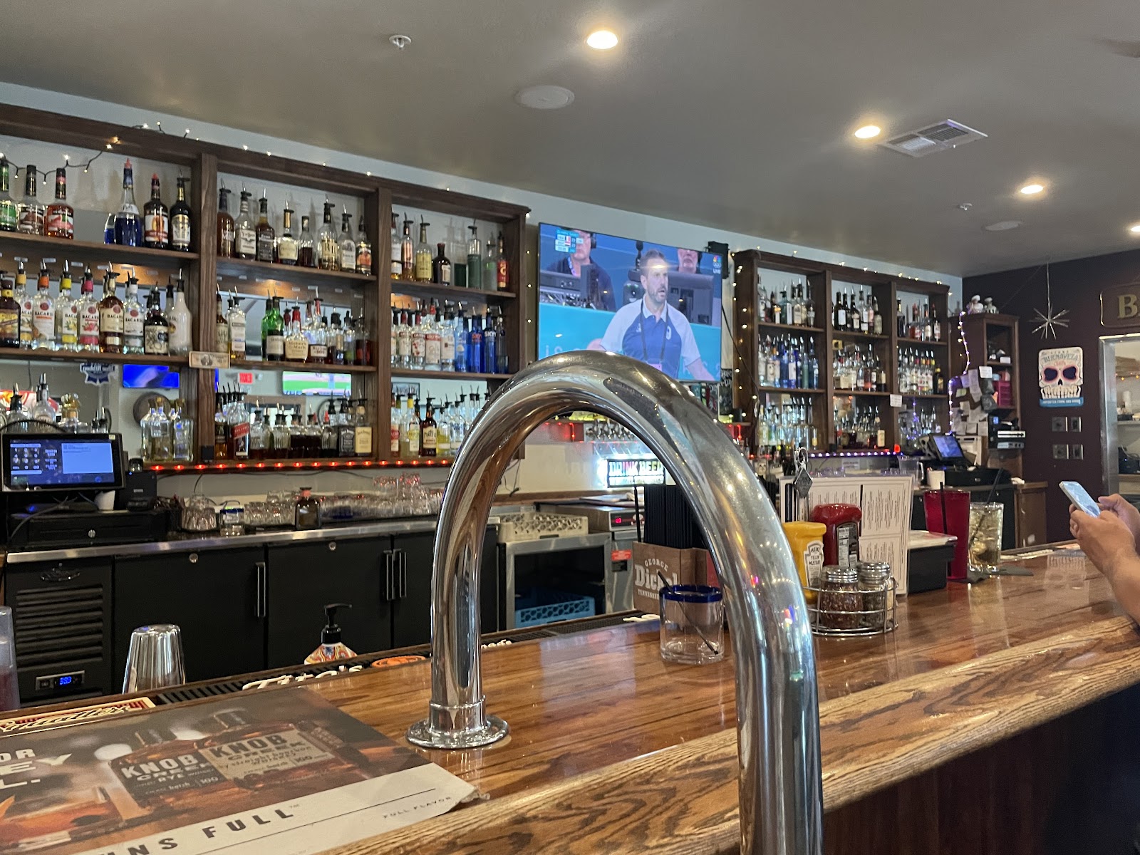 Interior at a Glacier National Park tavern bar with shelves of bottles and a curved chrome tap.