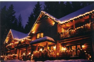 Snow-dusted lodge glows with string lights along Glacier National Park's timber cabins.