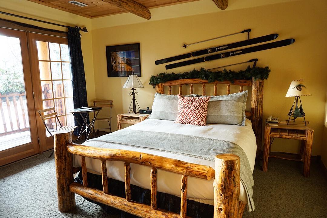 Cozy rustic lodge bedroom in Glacier National Park with a log bed and vintage ski decor on the wall.
