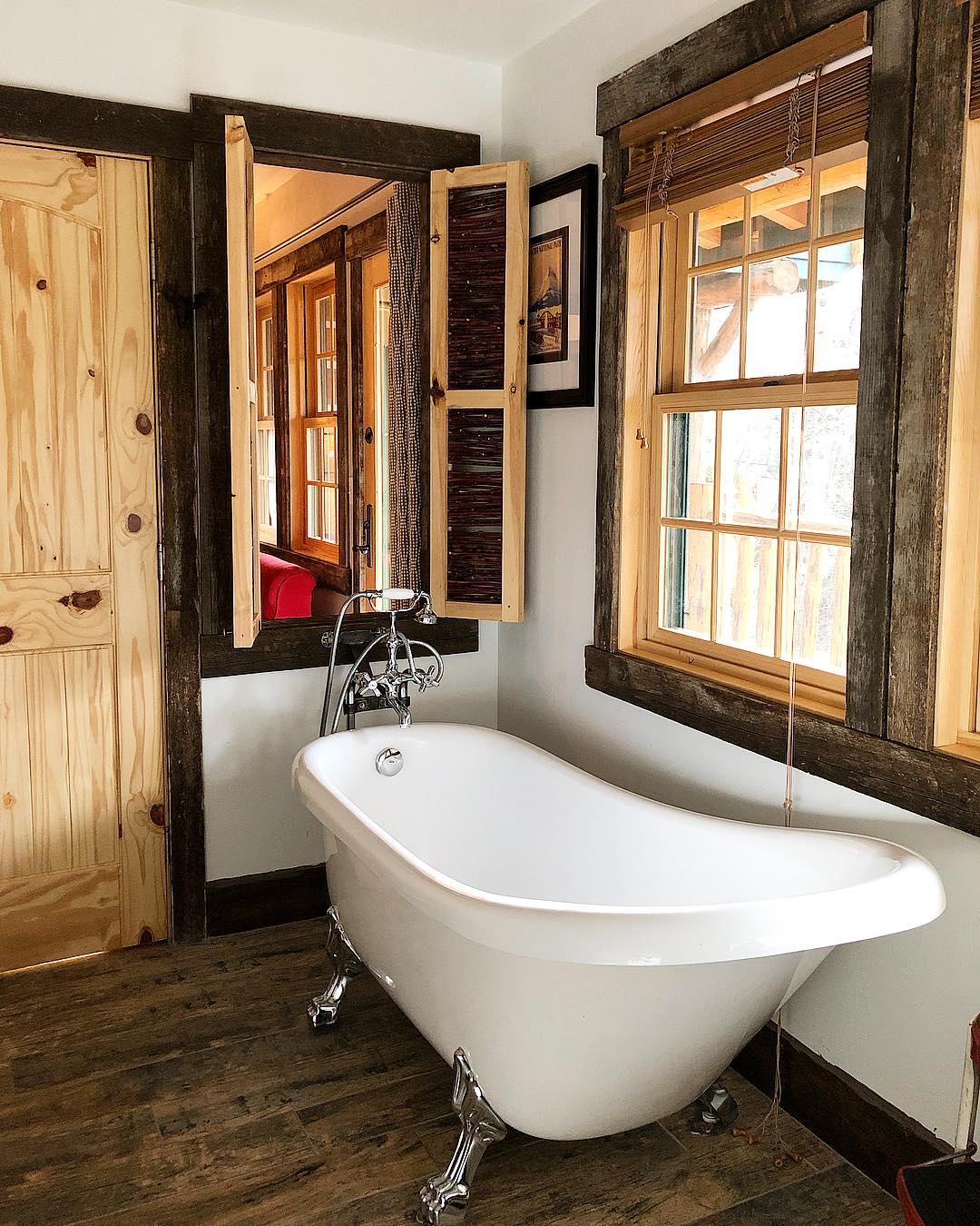 Rustic lodge bathroom in Glacier National Park featuring a porcelain clawfoot tub and dark wood trim.