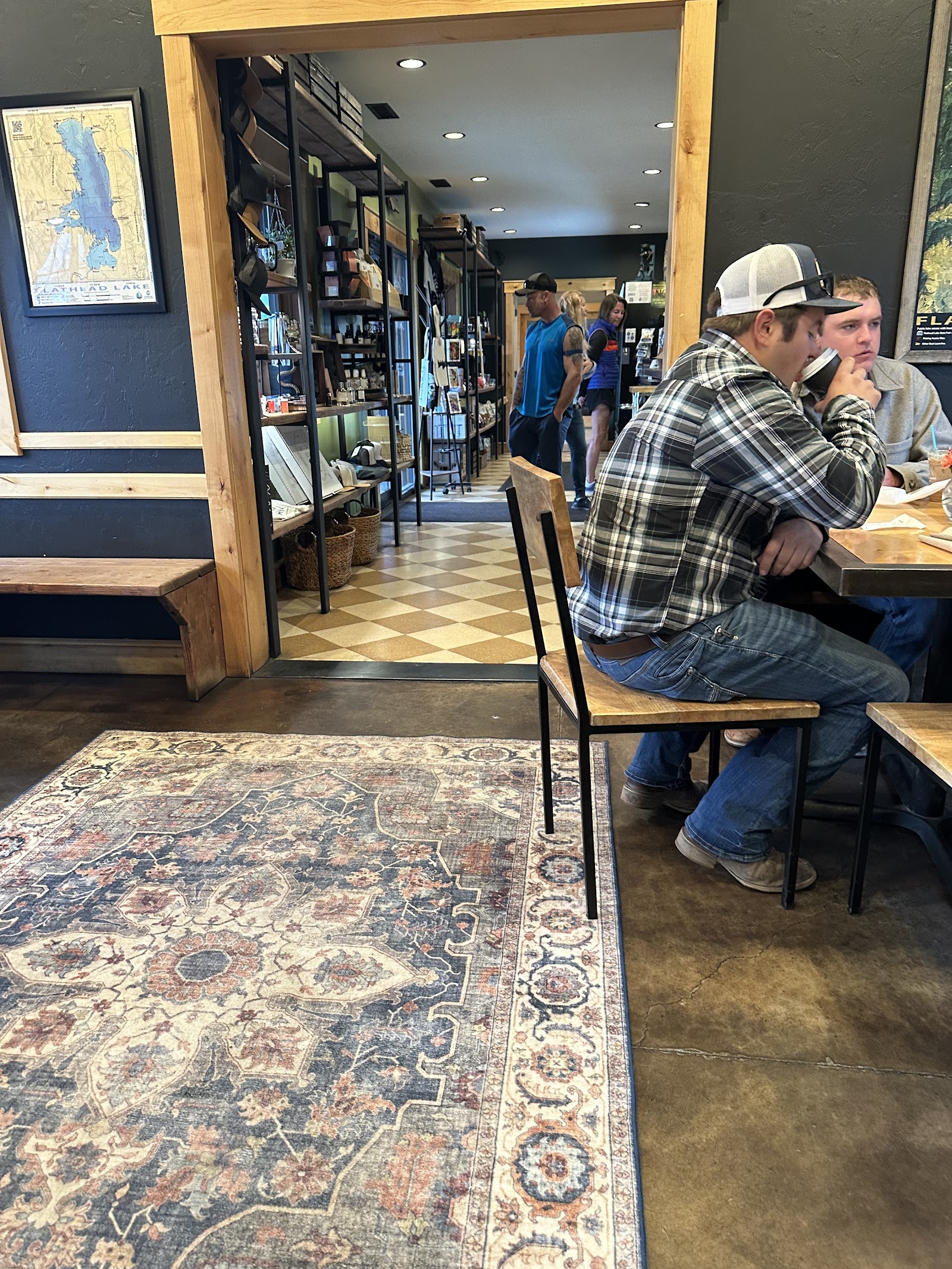 Cozy Glacier National Park cafe interior with a wooden table, patterned rug, and customers chatting inside.