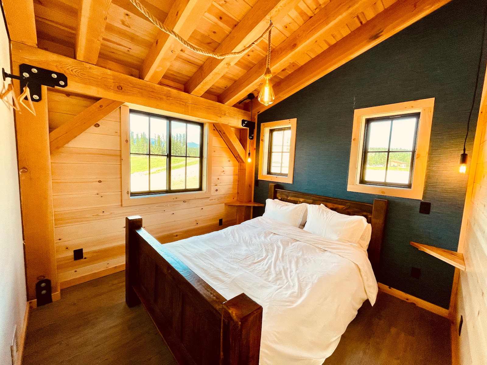 Cozy guest ranch bedroom inside Glacier National Park with warm wood walls, exposed beams, and a large bed.