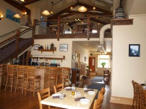 Three Forks Grille interior at Glacier National Park—wooden beams, warm lights, and a riverside-style bar.