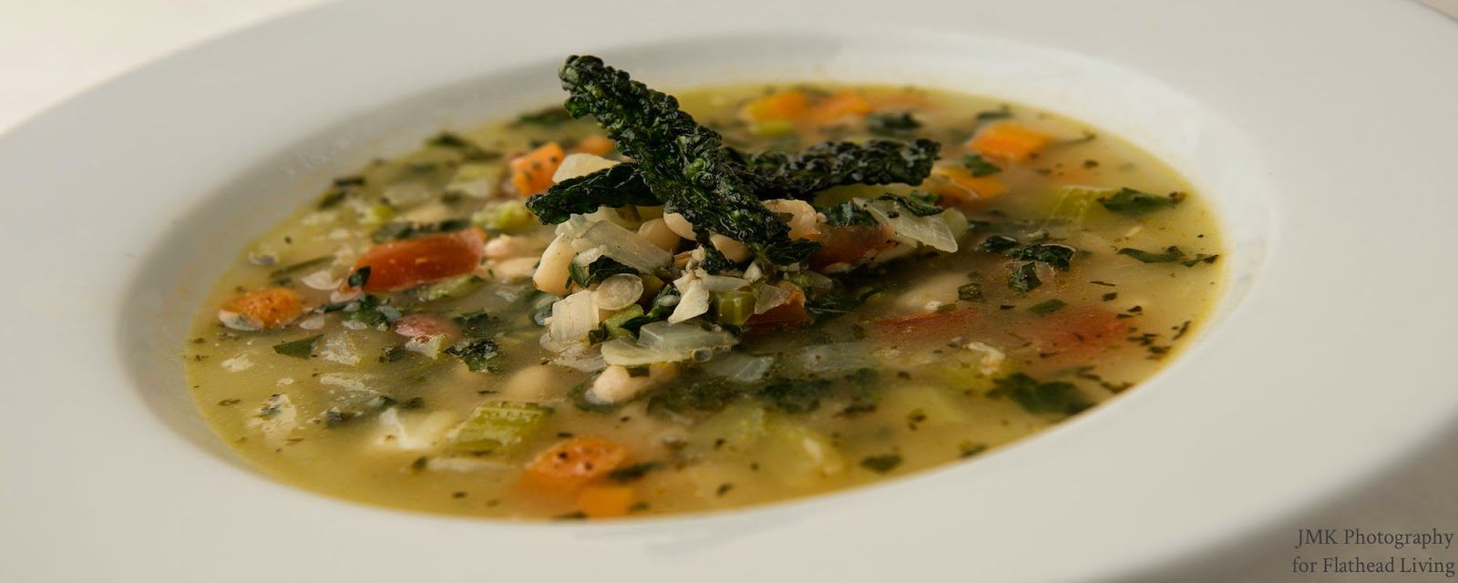 Soup in the dining area of a Glacier National Park restaurant, featuring visible vegetables and herbs in a light broth.