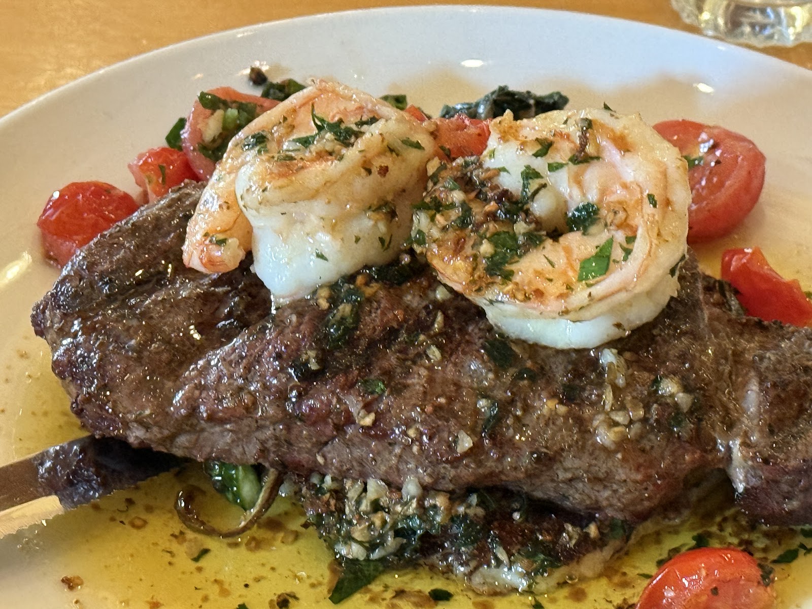 Seared steak topped with garlic-parsley shrimp, plated with tomatoes at Glacier National Park.