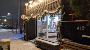 Snowy storefront of Glacier National Park ice cream shop in Whitefish, with garland and warm lights along the exterior.