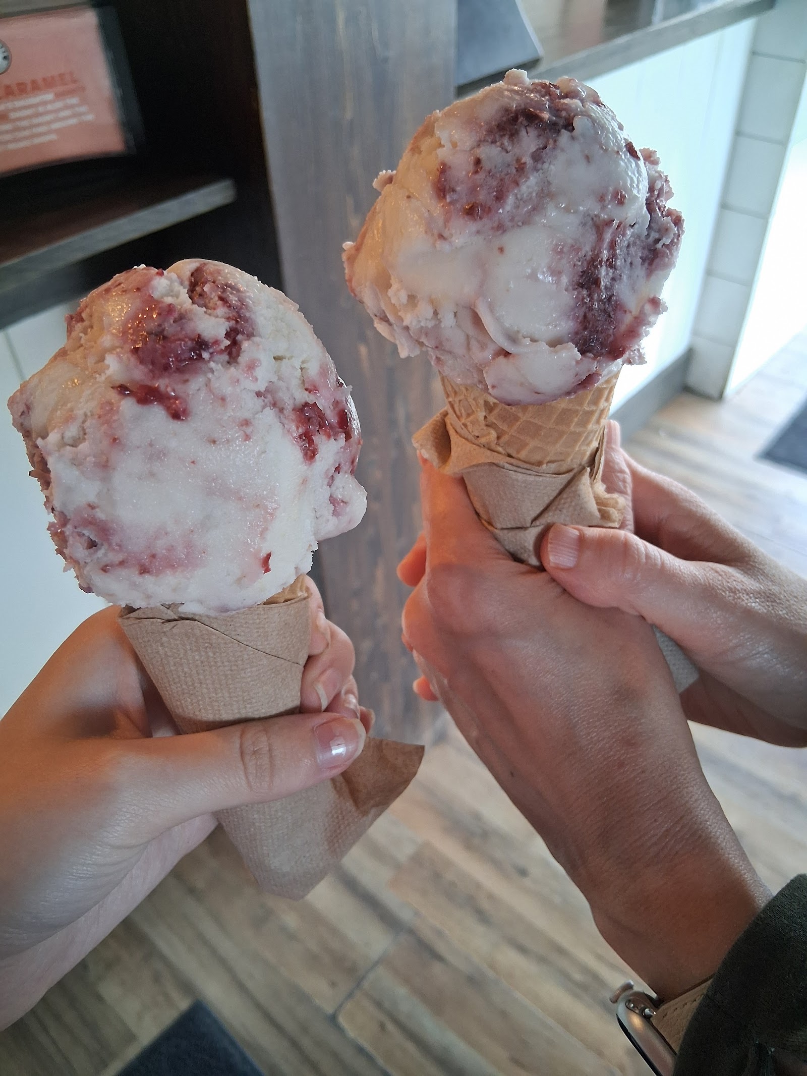 Two berry swirl ice cream cones held up inside Glacier National Park near Whitefish, ready to enjoy.