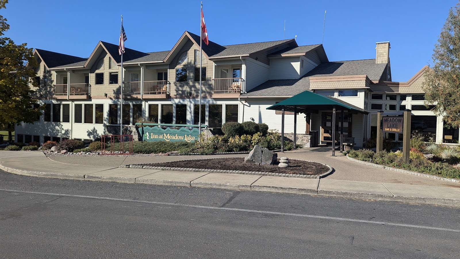 Inn at Meadow Lake lodge in Glacier National Park, a two-story building with flags, large windows, and a green entrance canopy.