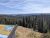Overlook sign in foreground, dense pine forest and distant layered hills under blue sky at Yellowstone National Park.