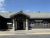 Front entrance of a visitor center with a peaked roof, gray siding, and windows in Yellowstone National Park.