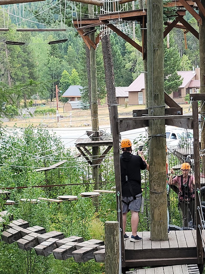 High ropes course platforms and suspended nets overlook a pine forest in Glacier National Park.