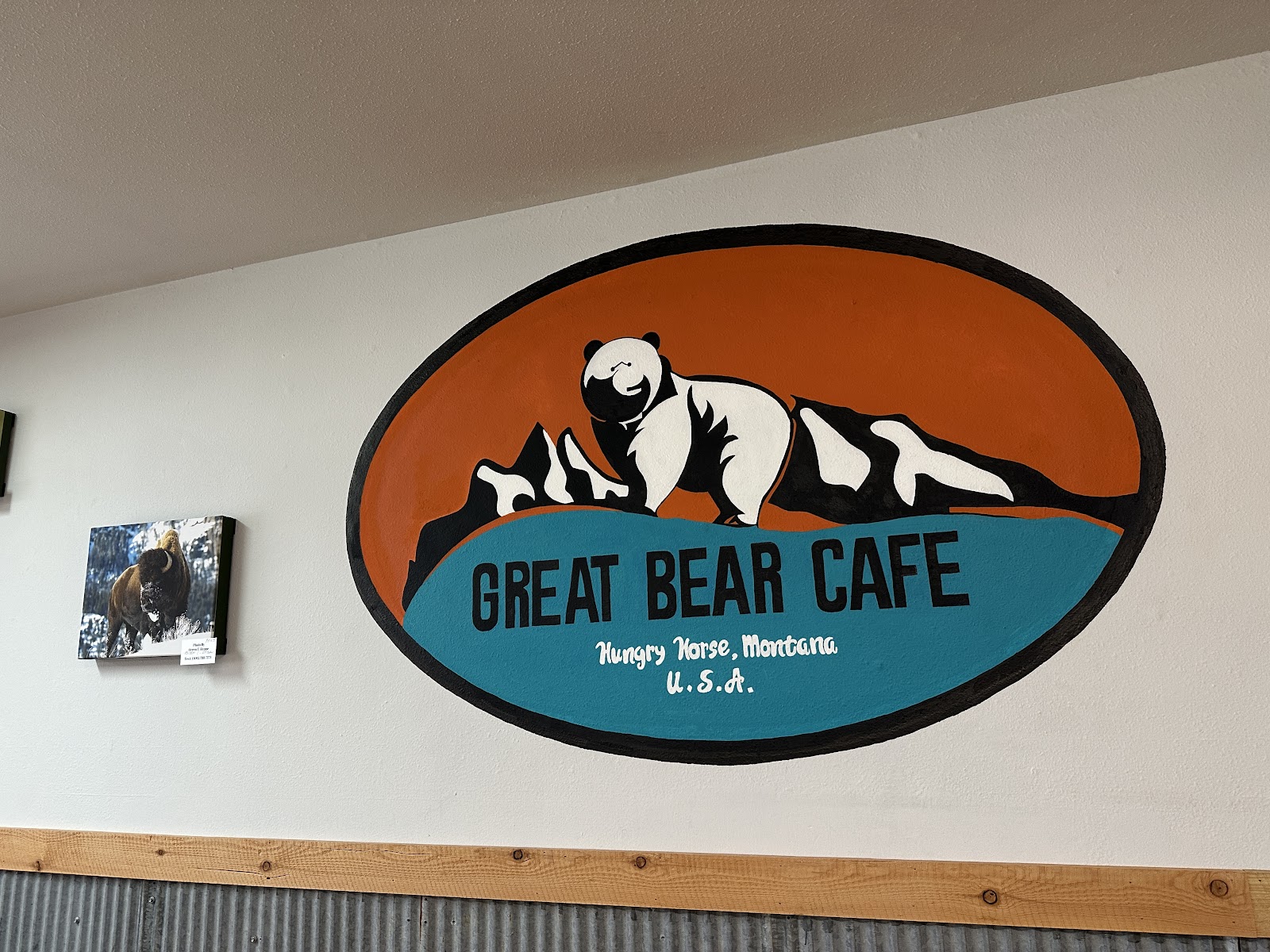 Bear-themed mural inside Glacier National Park highlighting a mountain landscape (canyon colors) in a cafe setting.