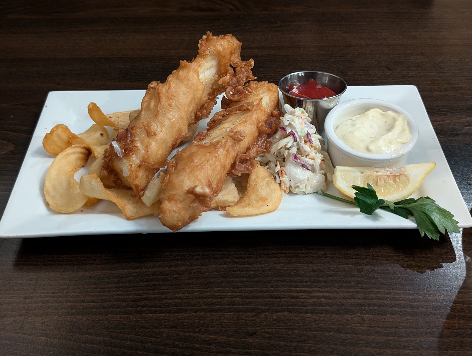 Golden fried fish and potato chips with coleslaw and dipping sauces at Meadow Lake Bar and Grille in Glacier National Park.