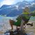 A person rests in a green portable chair at a glacier-fed lake with snow-capped peaks in Glacier National Park.