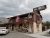 Exterior view of a two-story lodging building with flags, parked cars, and a gravel lot near Yellowstone National Park.