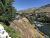 Lodging along the Yellowstone River with a pedestrian bridge and hillside town in Yellowstone National Park, seen under clear blue skies.