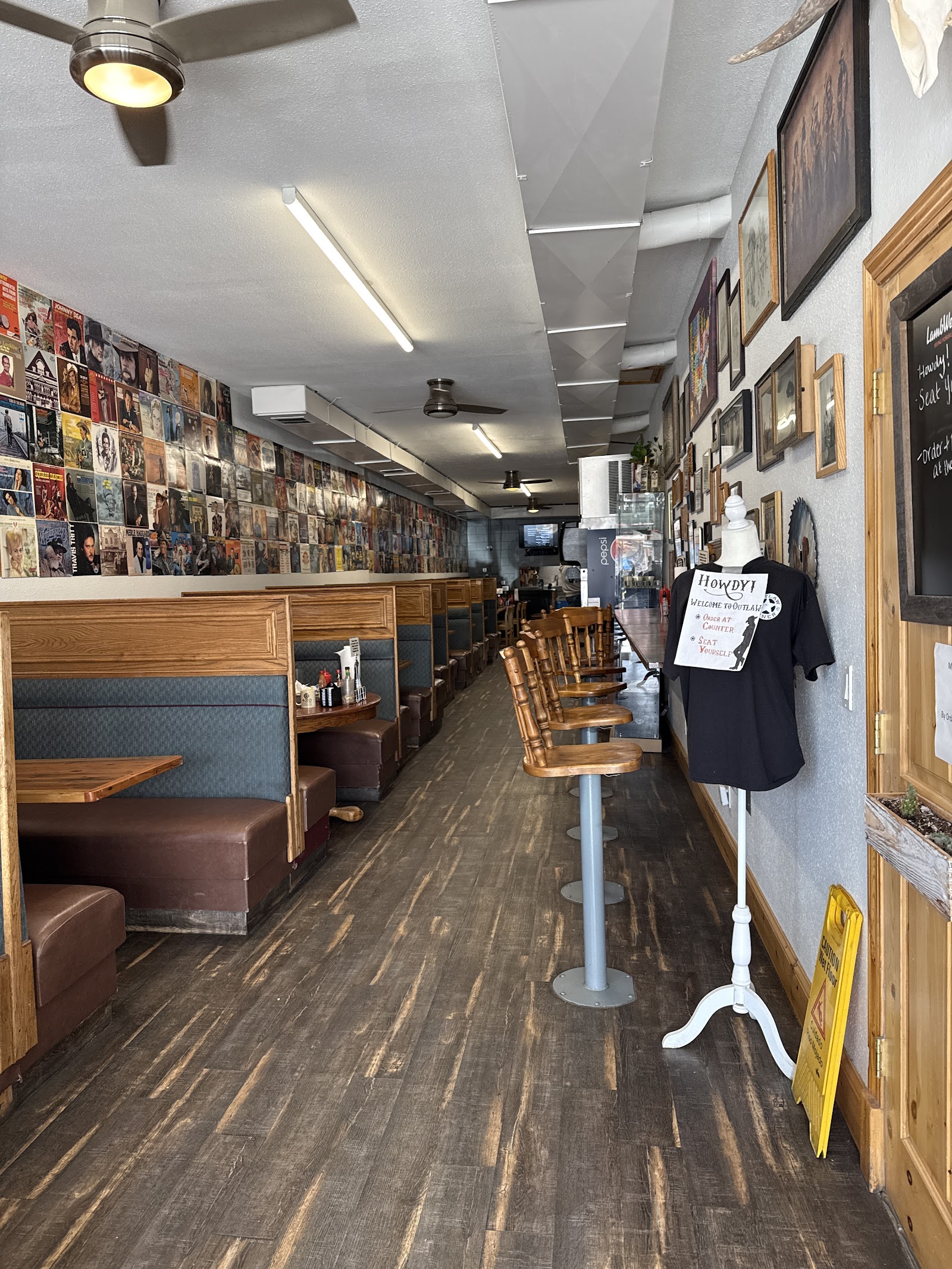Retro diner interior in Glacier National Park with booths along the left and wooden bar stools along the right, walls covered in posters.