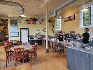 Inside a cafe at Glacier National Park, with wooden tables and a marble counter, warm lighting, and colorful decor.