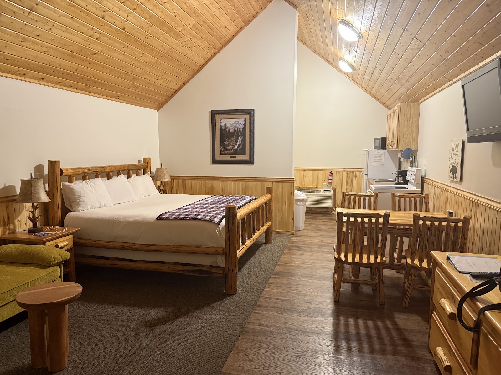 Rustic log-bedroom in Glacier National Park lodge, featuring a large wooden bed, pine walls, and cozy decor.