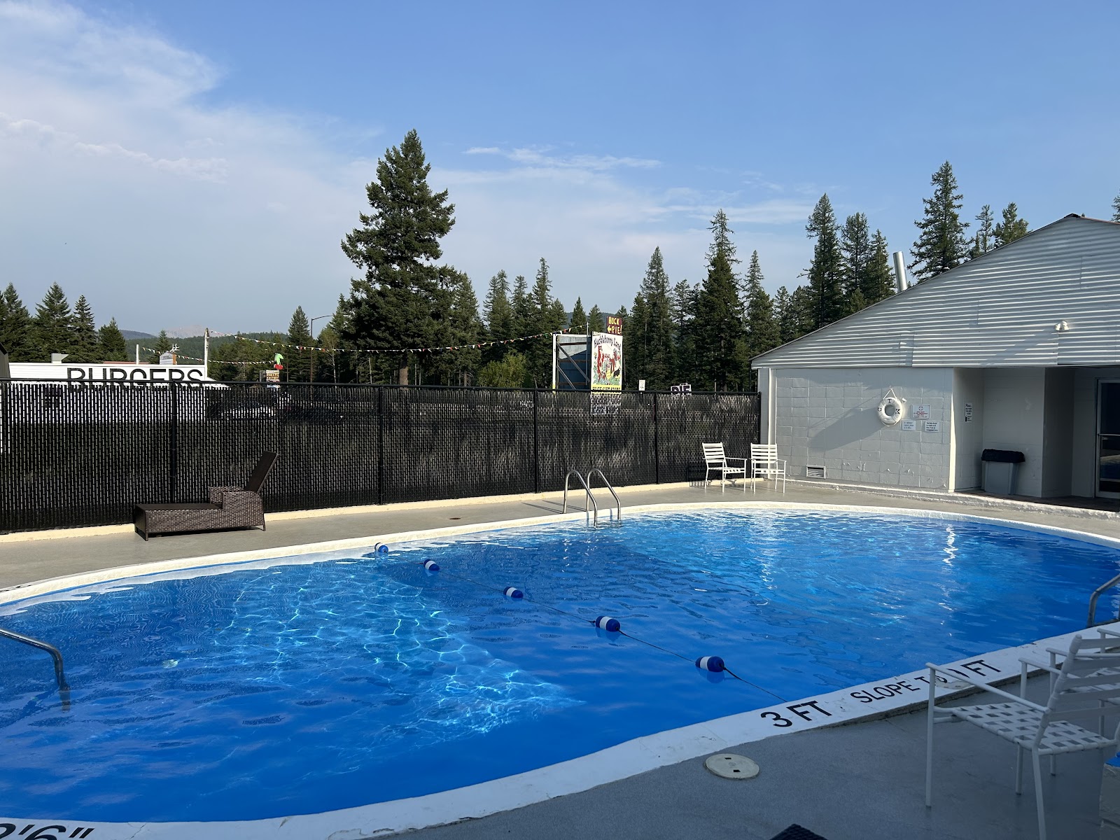 Pool area at Glacier National Park lodging and RV resort, with blue water and lounge chairs.