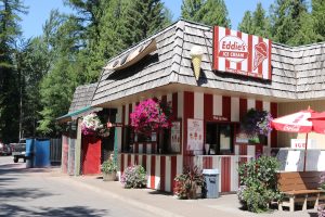 Gift shop exterior with striped red-and-white siding and hanging flower baskets in Glacier National Park.